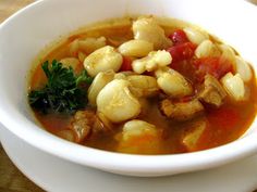 a white bowl filled with soup on top of a wooden table