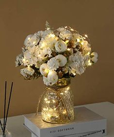 a vase filled with white flowers sitting on top of a table next to two candles