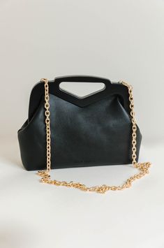 A staple handbag to add to your collection. The Black Triangle Handle Point Bag is made with a magnetic frame, v handle and a gold chain strap to wear on shoulders. The crossbody bag features one zip pocket and two slot pockets. Wear the black chain crossbody bag from everyday wear to special occasions. Luxury vegan leather 12"W x 6.5"H x 2.5"D Handle Drop: 3" Strap Length: 43" Magnetic Closure Gold-Tone Hardware Interior Zip & Slot Pockets Cotton Lining Fits up to an iPhone 11 Pro Max Everyday Clutch With Chain Strap, Modern Evening Bag With Chain Strap, Modern Evening Bag With Chain Strap For Everyday Use, Versatile Top Handle Evening Bag With Chain Strap, Modern Clutch With Chain Strap For Everyday, Modern Satchel With Chain Strap For Everyday Use, Everyday Clutch With Chain Strap And Top Handle, Evening Satchel With Chain Strap And Double Handle, Everyday Double Handle Satchel With Chain Strap