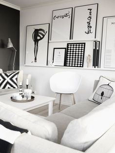 a living room filled with white furniture and pictures on the wall above it's coffee table