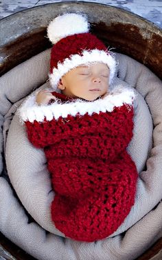 a newborn baby wearing a santa hat and sleeping in a crocheted basket