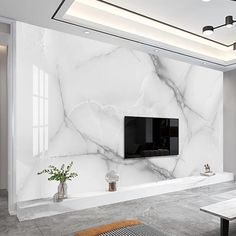 a living room with white marble walls and flooring, tv on the wall in the center