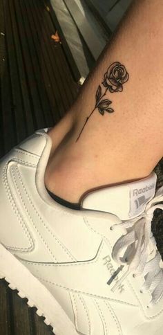 a woman's foot with a rose tattoo on her left leg and white sneakers