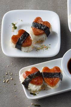 sushi is served on small white plates with sauces and seasoning in bowls