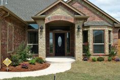 a brick and stone house with landscaping around the front door is shown in this image