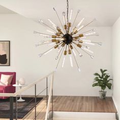 a chandelier hanging from the ceiling in a living room with stairs leading up to it