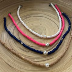 three necklaces with pearls and beads on a wooden surface in the shape of a circle