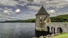 an old stone building sitting on the side of a lake