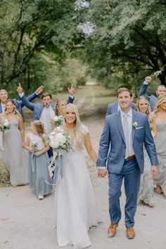 a bride and groom walking with their bridal party