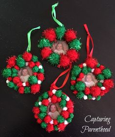 three red and green christmas ornaments with two pictures hanging from them on a black surface