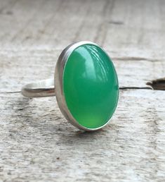 This bright green chrysoprase has been set in sterling silver with a handmade ring band from sterling silver half dome wire. This ring is simple and elegant. The lovely bright green chrysoprase is 18mm x 13mm in size. Made to order! Green Oval Chalcedony Rings, Oval Green Chalcedony Rings, Handmade Green Oval Cabochon Ring, Green Chalcedony Gemstone Rings, Chrysoprase Emerald Ring With Oval Cabochon For Gift, Handmade Green Chalcedony Rings, Green Chrysoprase Cabochon Rings, Handmade Green Rings For Everyday Wear, Handmade Green Rings For Everyday