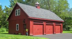 a red barn with two garage doors and a steeple