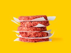 three hamburger patties stacked on top of each other in front of a yellow background