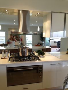 a woman is standing in the kitchen with her reflection in the mirror and cooking on the stove