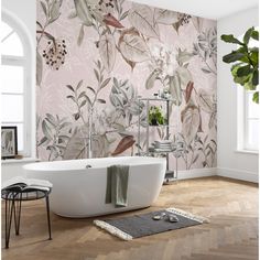 a bath tub sitting in front of a window next to a potted plant on top of a wooden floor