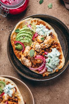 two flatbreads with chicken, guacamole and avocado on them