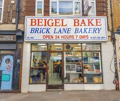 a store front with an open sign on it's side and people standing in the doorway