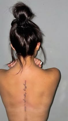 the back of a woman's upper body with writing on her left shoulder and right arm