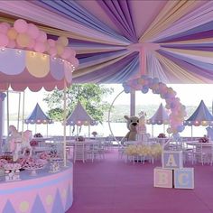 a pink and purple decorated party with balloons, decorations and teddy bear on the carousel