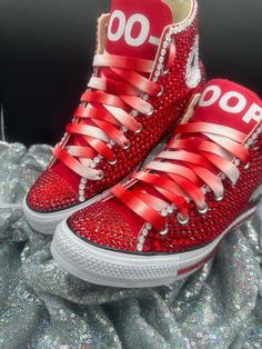 a pair of red sneakers with white laces and bows on the side, all covered in sequins