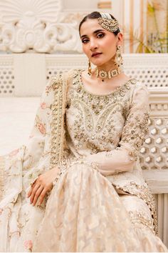 a woman sitting on top of a white bench wearing a dress and headpieces