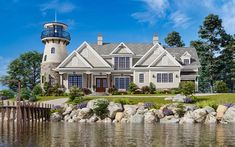 a large white house with a lighthouse on top of it's roof next to the water