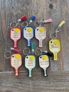 six key chains with different colors and styles of tennis racquets on them