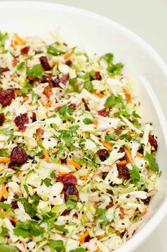 a salad with cranberries, celery, carrots and lettuce in a white bowl