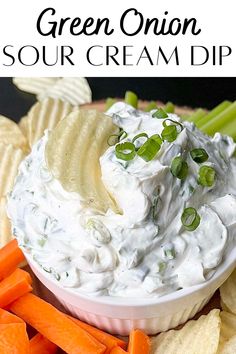 a bowl filled with sour cream dip surrounded by carrots and crackers