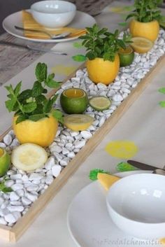 the table is set with lemons, limes and other fruit on rocks in an arrangement