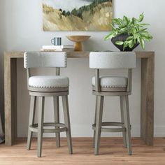 two stools in front of a table with a painting on the wall behind them