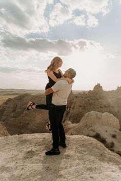 a man holding a woman on top of a mountain