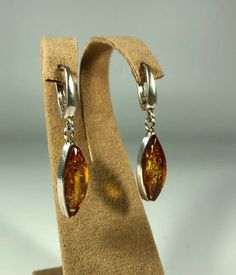 Elevate your style with our Handmade Earrings featuring spectacular orange amber set in textured 925 sterling silver. These exquisite earrings are designed for women who appreciate unique and original jewelry. The vibrant orange amber stones are beautifully complemented by the textured silver, creating a stunning and eye-catching piece that adds a touch of elegance and sophistication to any outfit. Product Details: Material: 925 Sterling Silver Stone: Orange Design: Textured Silver with Unique S Modern Orange Sterling Silver Jewelry, Classic Amber Sterling Silver Earrings, Luxury Amber Drop Earrings, Modern Amber Drop Earrings, Orange Teardrop Sterling Silver Earrings, Elegant Amber Sterling Silver Earrings, Elegant Orange Sterling Silver Earrings, Luxury Amber Jewelry With Matching Earrings, Amber Sterling Silver Dangle Earrings