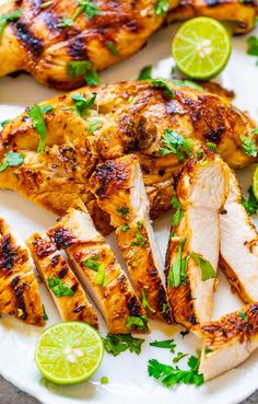 grilled chicken with limes and cilantro on a white plate