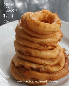 a stack of fried onion rings on a white plate with the words beer battered deep fried onion rings