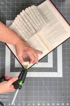 a person is cutting up an open book with scissors and glue on top of it