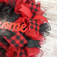 a red and black wreath with the word home on it, sitting on a wooden surface