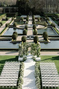 an outdoor ceremony setup with rows of white chairs and flowers on each side of the aisle