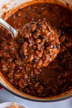 a spoon full of chili and beans in a pot