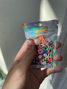 someone is holding up a bag of buttons in their left hand and there are other items inside the package