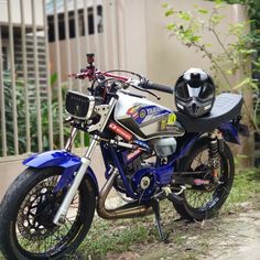 a blue and silver motorcycle parked next to a fence