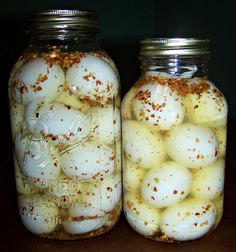 two jars filled with eggs on top of a wooden table