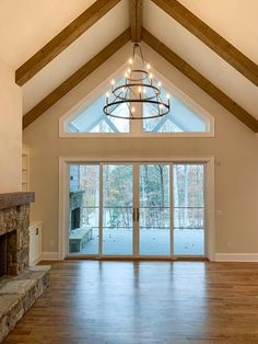 an empty living room with wood floors and a chandelier hanging from the ceiling