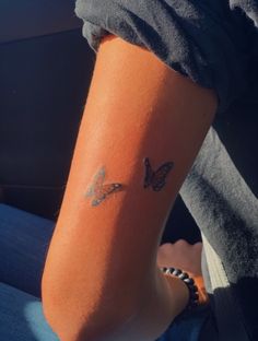 a woman with a butterfly tattoo on her arm sitting in the back seat of a car