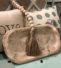 decorative ceramic bowl with tasseled beads and bead necklace on display in front of pillows