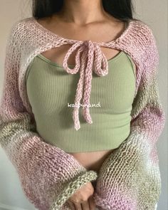 a woman wearing a crop top and sweater with her hands on her hips, posing for the camera