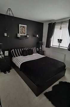 a black and white bedroom with striped bedding, nightstands and pictures on the wall