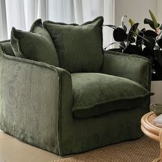 a green chair sitting on top of a rug next to a plant in a vase