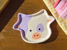 a pig shaped dish sitting on top of a wooden table next to a pink toothbrush