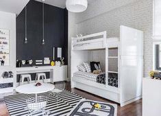 a white bunk bed sitting in a bedroom next to a table and chair on top of a black and white rug